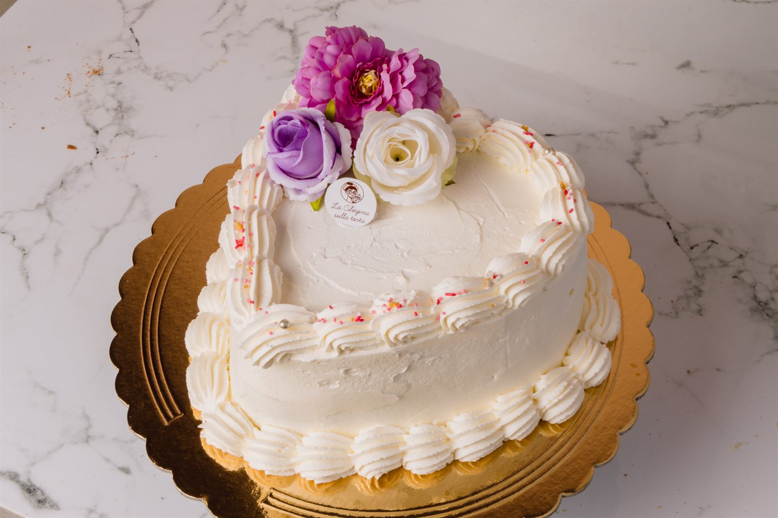 Torta a cuore decorata con panna e fiori